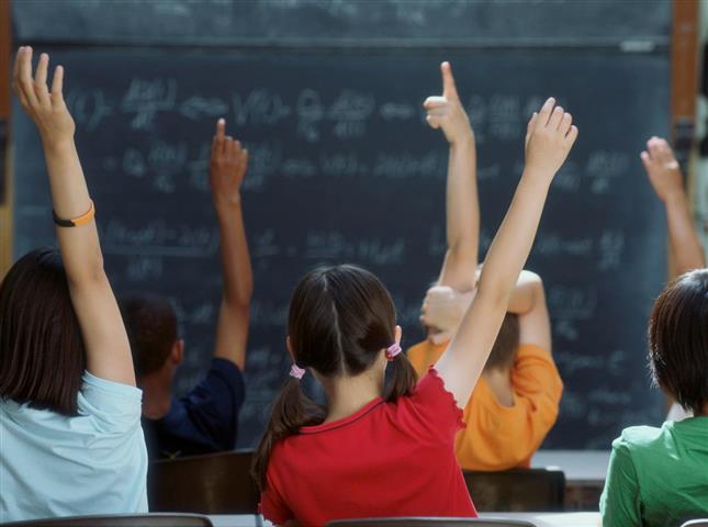 Children raising their hands in school